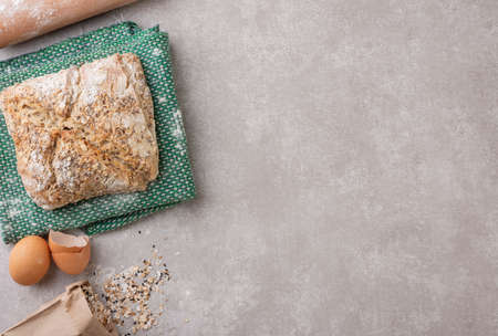 Whole bread over cloth with flour, eggs and rolling pin over concrete background. Top view.