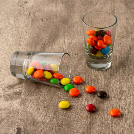 Colorful candies on glasses and spread over wooden table