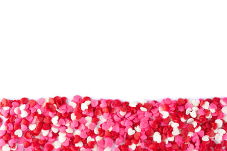 Top closeup view of a group of red, white and pink heart shaped candies over white background with...