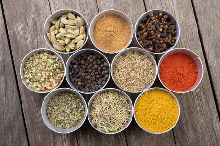 Seasonings on metallic bowls over wooden table.の写真素材