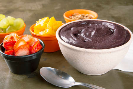 AÃ§aÃ­ on a white bowl with strawberry, mango and grape on colorful bowls over a stone backgroundの写真素材
