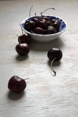 Black cherries on a white and blue vintage bowl over wooden table