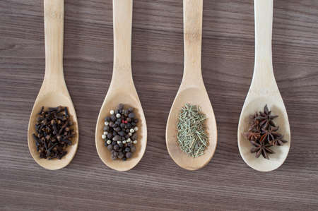 Seasonings on spoons over wood background