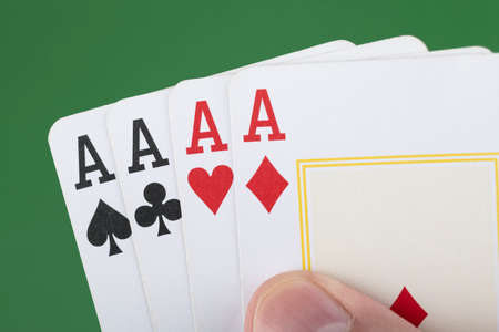 Hand holding 4 aces cards over green background.の写真素材