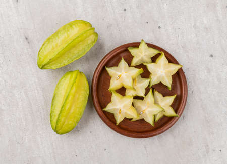 Starfruits with slices over a wooden plate.の写真素材