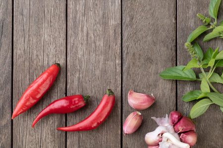 Red chili peppers and other seasonings over wooden table with copy space.の写真素材