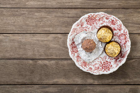 Hazelnut filled chocolates on a plate over wooden table with copy space.の写真素材