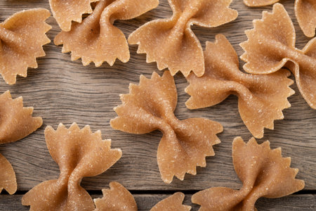 Narrow focus closeup of whole wheat farfalle pasta over wooden table.の写真素材
