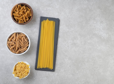 Assorted pasta over concrete countertop with copy space.の写真素材