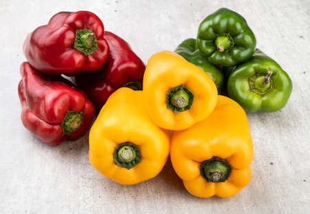 Green, red and yellow bell peppers over rustic background.の写真素材