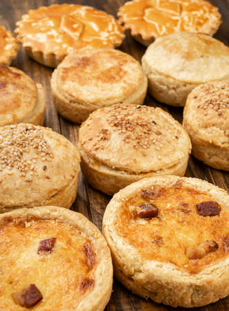 Assorted homemade pies and quiches over wooden table.の写真素材