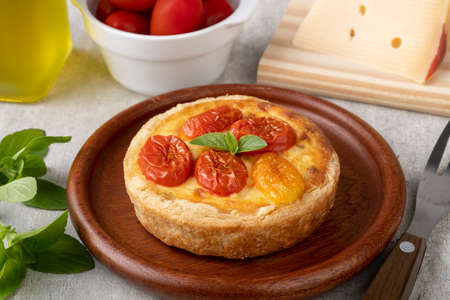 Homemade caprese quiche over wooden plate with ingredients.の写真素材