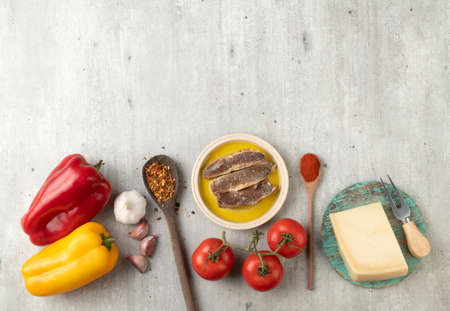 Tomatoes, bell peppers, fish, parmesan cheese and garlic over wooden table with copy space. Mediterranean food.の写真素材