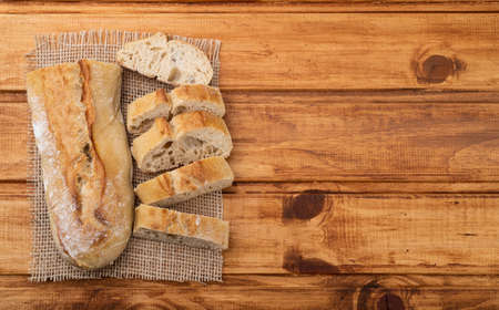 Traditional homemade french baguette bread with slices over wooden table with copy space.の写真素材