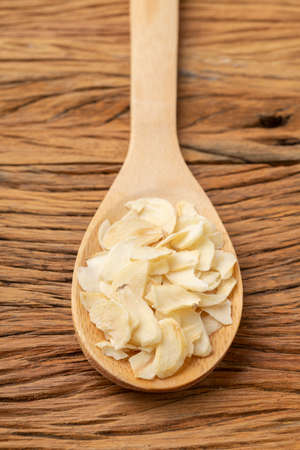 Closeup of dried garlic slices on a wooden spoon. Food backdrop.の写真素材
