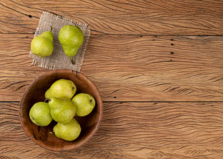 Green pears in a bowl over wooden table with copy space.の写真素材