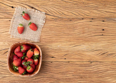 Strawberries in a bowl over wooden table with copy space.の写真素材