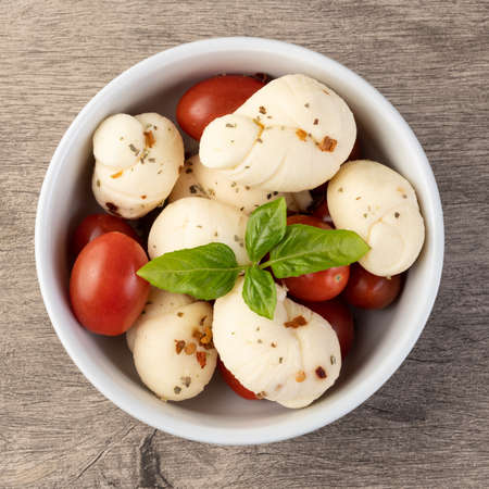 Nozinho or Knot mozzarella, typical brazilian artisanal fresh white cheese with seasonings, basil and cherry tomatoes.の写真素材