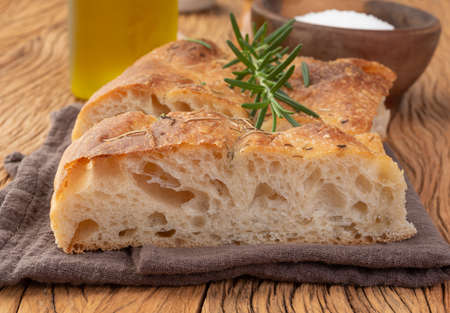 Home made focaccia with salt, olive oil and rosemary over wooden table.