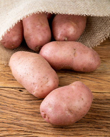 Red potato on a bag over wooden table.の写真素材