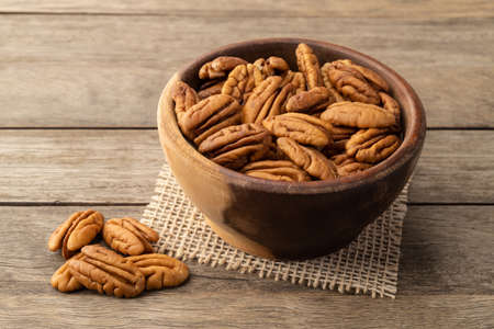 Pecan nuts in a bowl over wooden table.