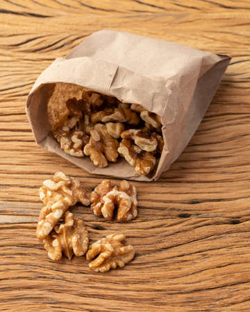 Walnuts in a paper bag over wooden table.の写真素材