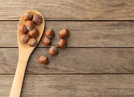 Shelled hazelnuts in a spoon over wooden table with copy space.の写真素材