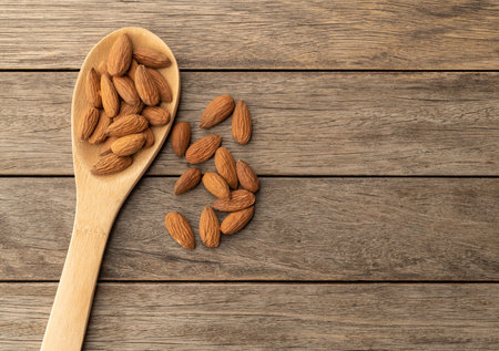 Almonds in a spoon over wooden table with copy space.の写真素材