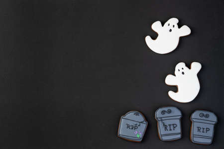 Halloween gingerbreads, ghost, tombstone over black background with copy space.