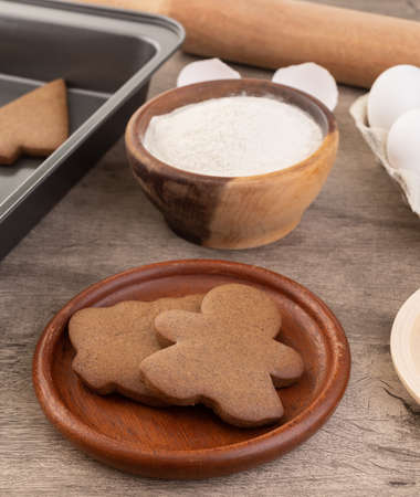 Traditional christmas gingerbread cookies over a wooden table with ingredients.