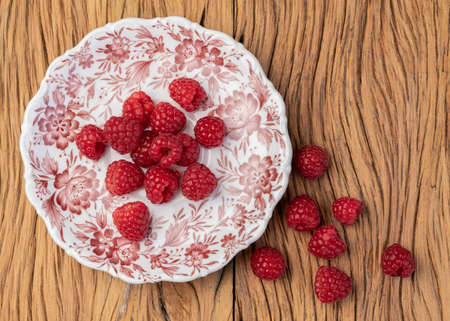 Raspberries in a plate over wooden table.