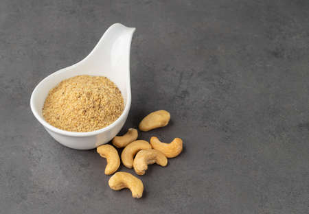 Cashew nut flour in a bowl over stone background. Gluten free flour.