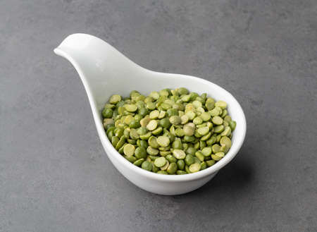 Raw dried green peas in a bowl over stone background.
