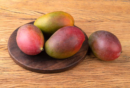 A group of ripe mangos over wooden board.の写真素材
