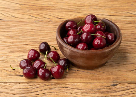 Red cherries on a bowl over wooden table.の写真素材