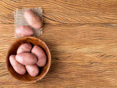 Red potato in a basket over wooden table with copy space.の写真素材