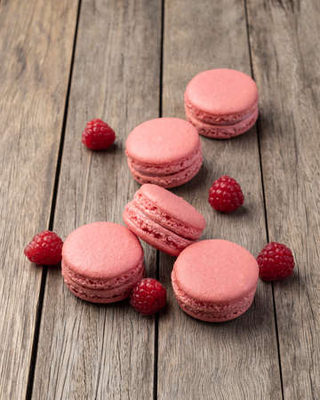Berry macarons with raspberries over wooden table.の写真素材
