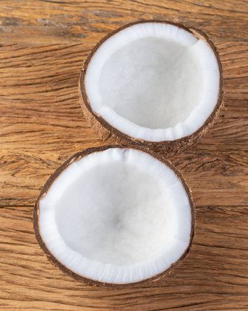Cracked coconut half fruit over wooden table.