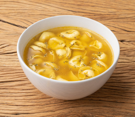 Cappelletti or tortellini brodo soup in a bowl over wooden table.の写真素材