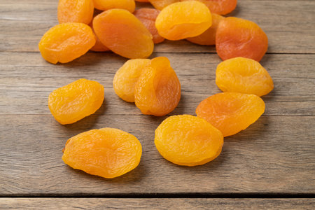 A group of dried apricots over wooden table.の写真素材