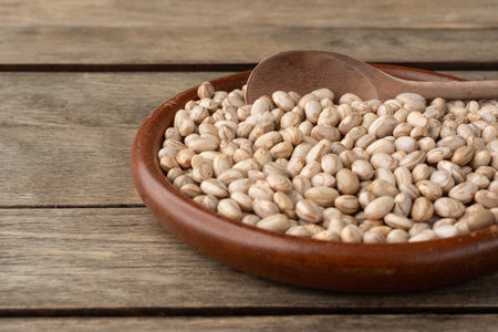 Brown beans on a plate over wooden table. Short depth of field.