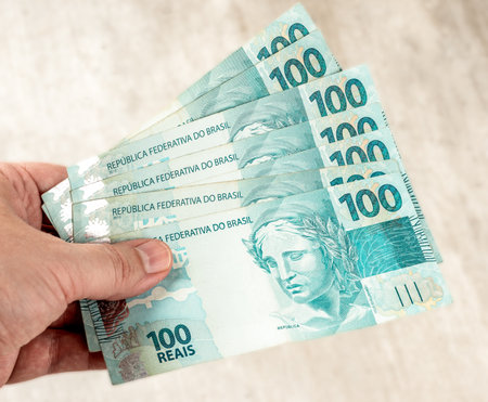 Hand holding hundred brazilian real bills.の写真素材