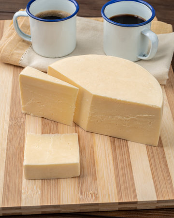 Artisanal Alagoa cheese from Minas Gerais, Brazil over a wooden board with coffee.