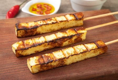 Grilled Rennet or Coalho cheese on a wooden board with sugar syrup and pepper.の写真素材