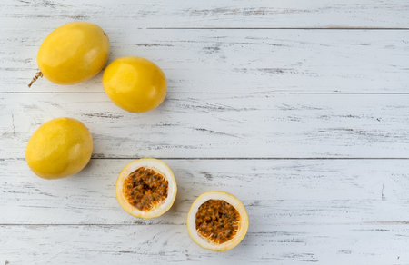 Passion fruits with cut fruit over wooden table with copy space.