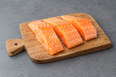 Raw salmon slices with on wooden board over stone background.の写真素材