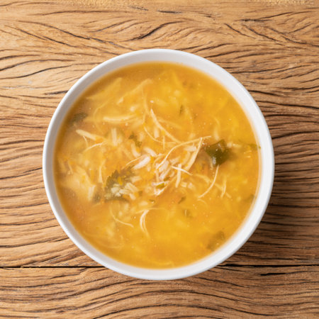 Chicken soup in a bowl over wooden table.の写真素材