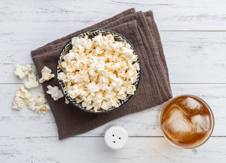 Popcorns on a bowl with salt over and soda wooden table.の写真素材