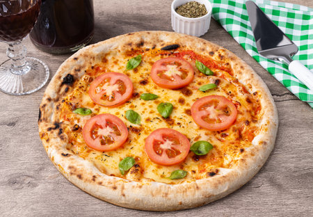 Margherita style pizza over wooden table with wine, oregano and spatula.の写真素材