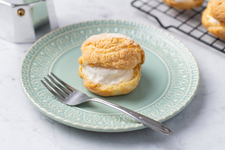 Choux cream, vanilla whipped cream stuffed cake on a green plate.の写真素材